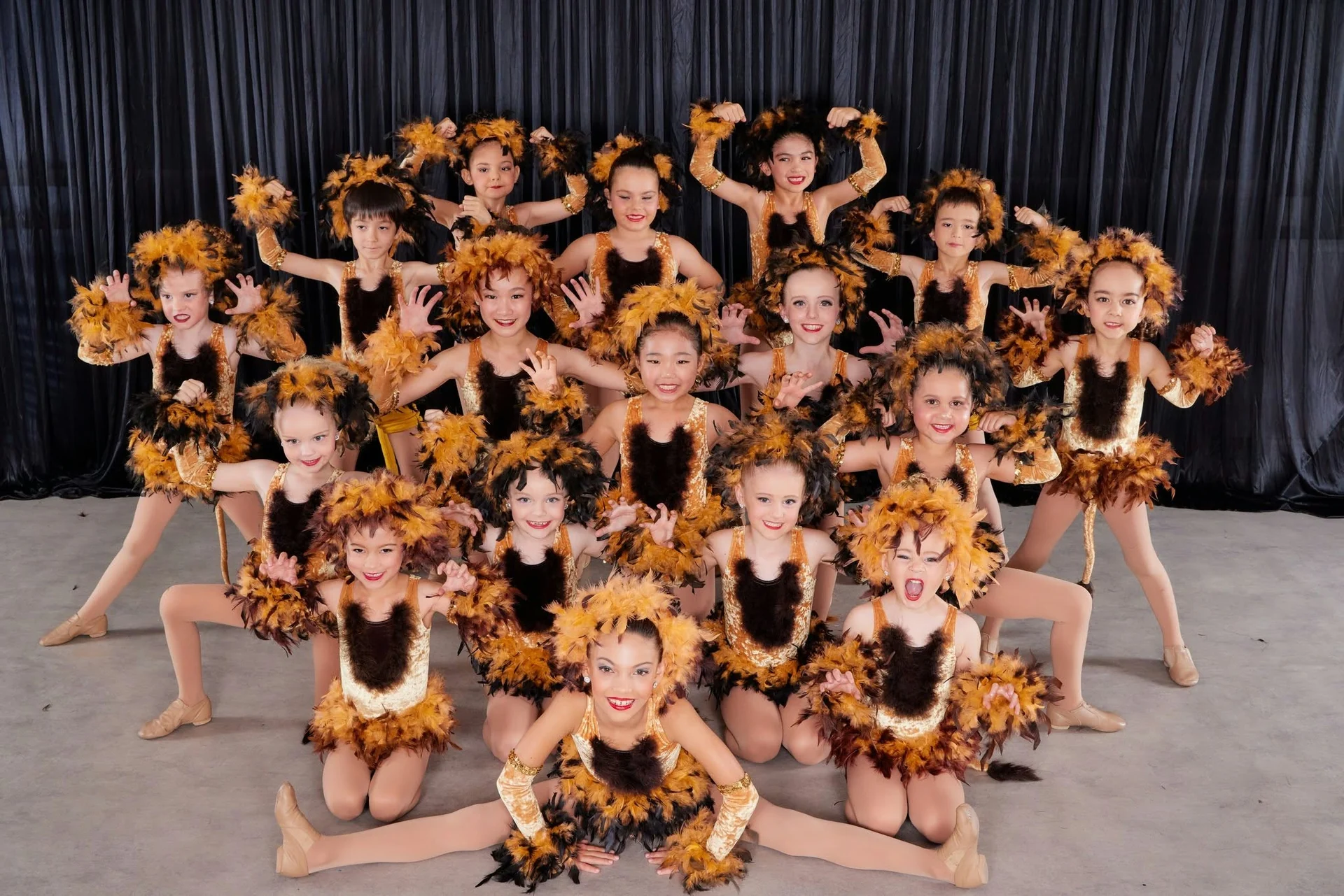 Young JMDS dancers in feathered lion costumes, roaring and clawing for the camera